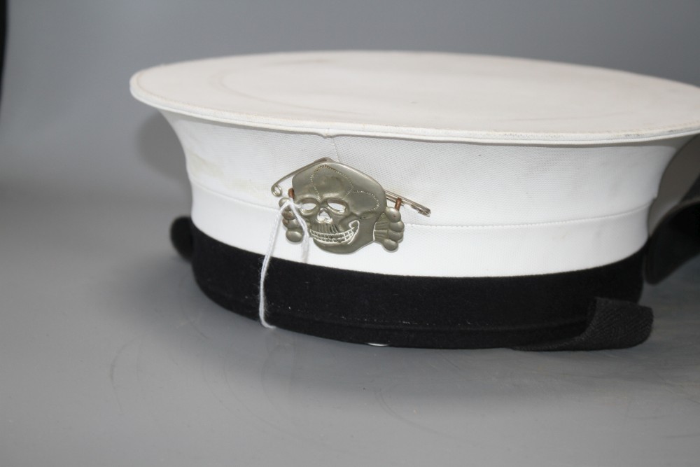A Russian sailors cap with numbered label and attached skull and crossbones badge, and a steel helmet with original leather fittings